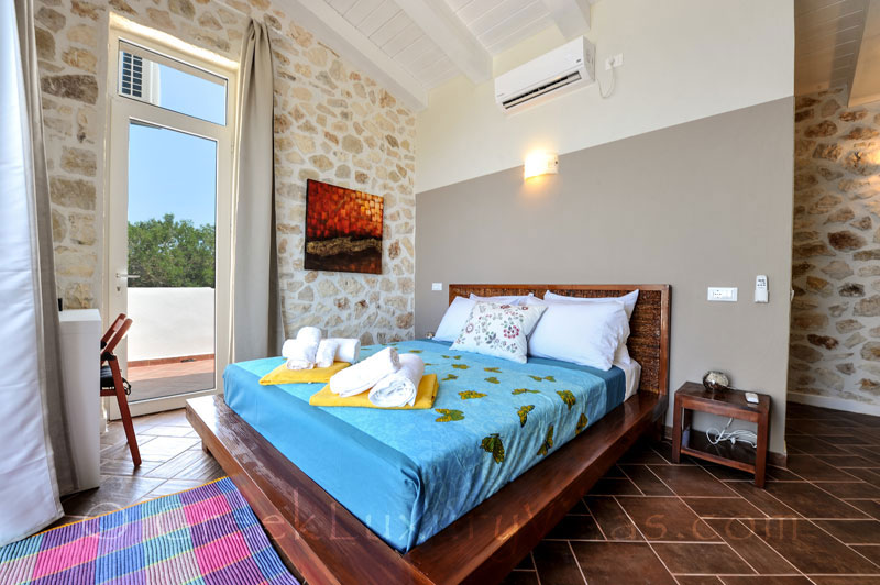 A bedroom of a cheerfully decorated villa with a pool and seaview in Paxos