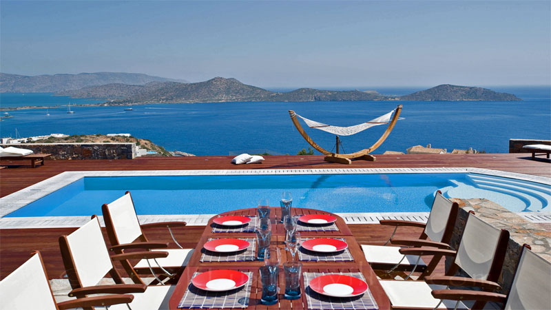 Outdoor dining area of a modern luxury villa overlooking Elounda bay