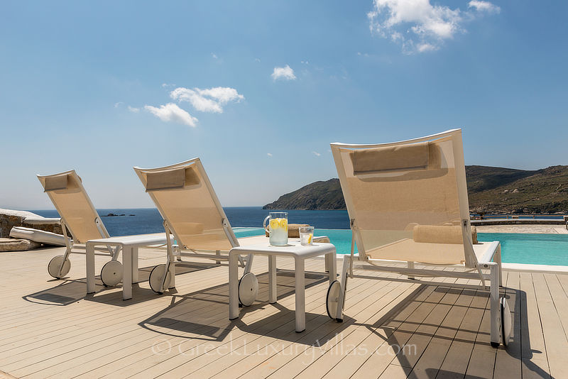 Sonnenliegen einer Luxusvilla mit Pool am Strand von Kalo Livadi